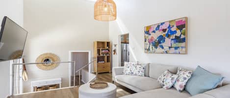 A modern living room with a sofa, a television, a bookshelf, and a painting on the wall.