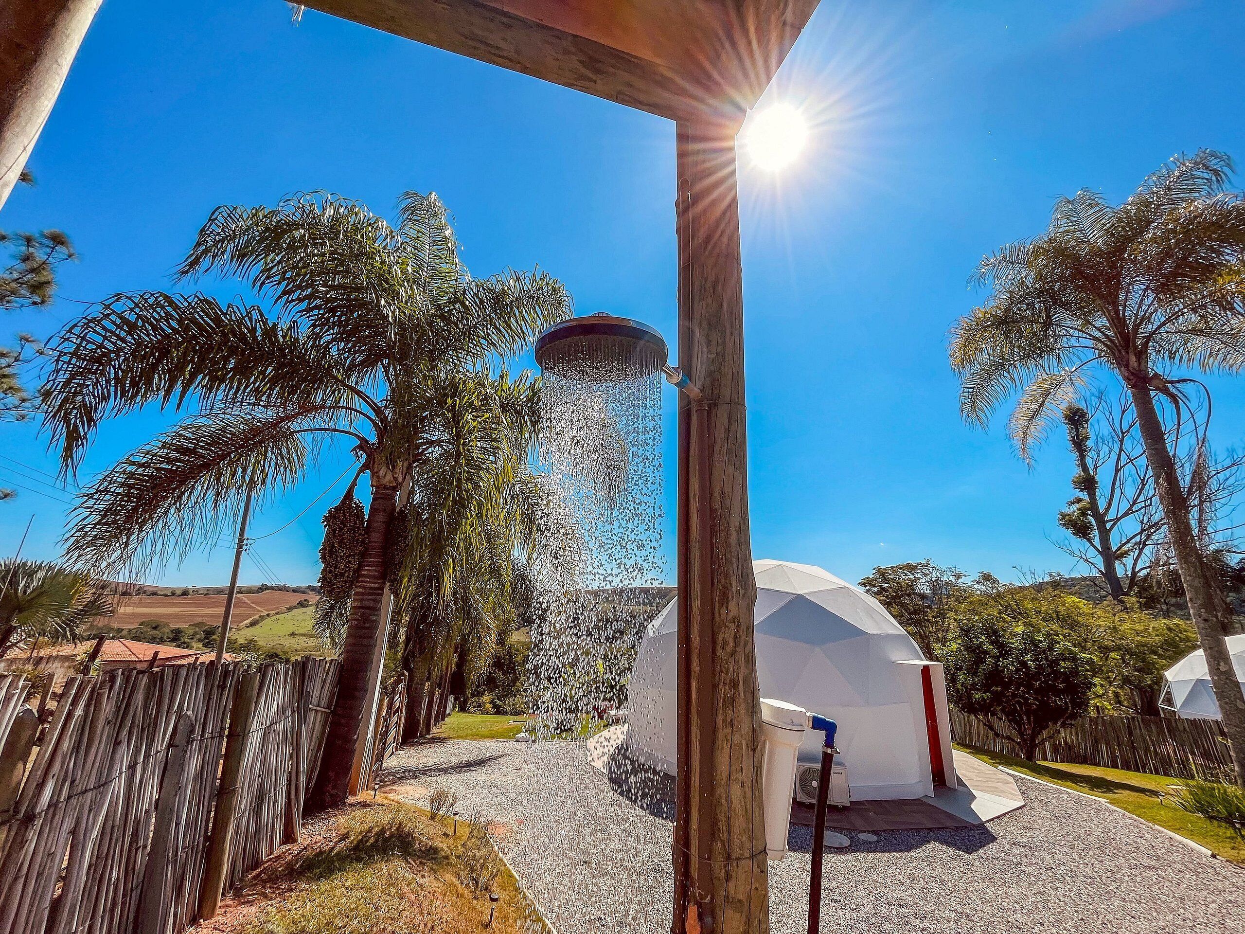 A water feature with a fountain, a white dome structure, and palm trees in a sunny outdoor setting.