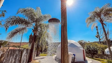 A water feature with a fountain, a white dome structure, and palm trees in a sunny outdoor setting.