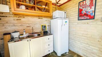 Una cucina compatta con un frigorifero bianco, un pensile in legno con vetri e un lavello.