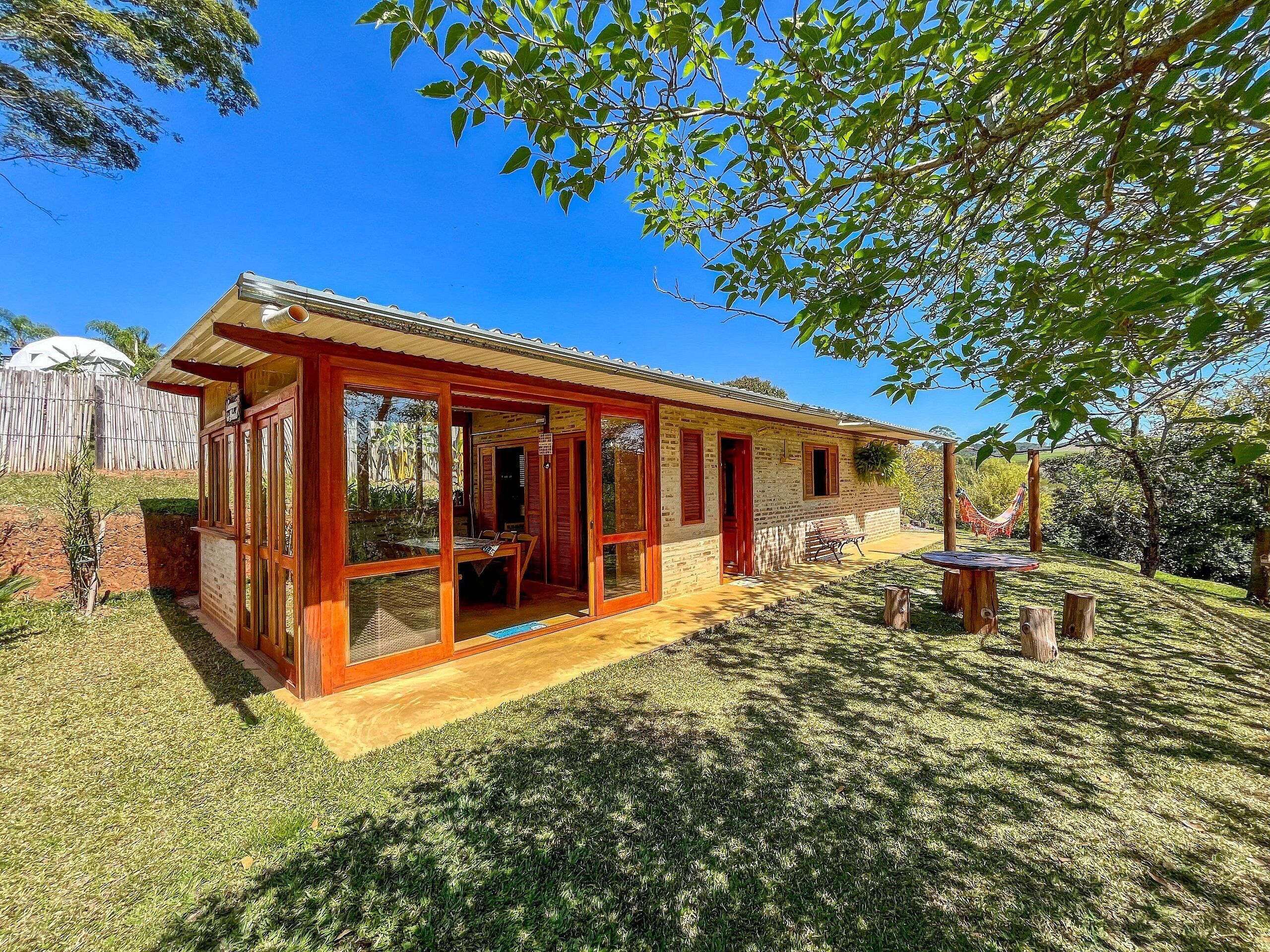 A single-story house with a wooden exterior, large glass doors, and a covered patio area.