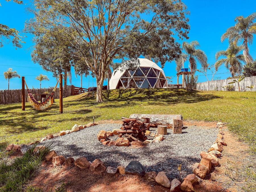 A geodesic dome structure surrounded by trees and a hammock.