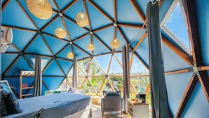 A modern, geometric interior with a large bed, seating area, and a view of greenery outside. - Rua José Joaquim Nogueira (Santa Branca)