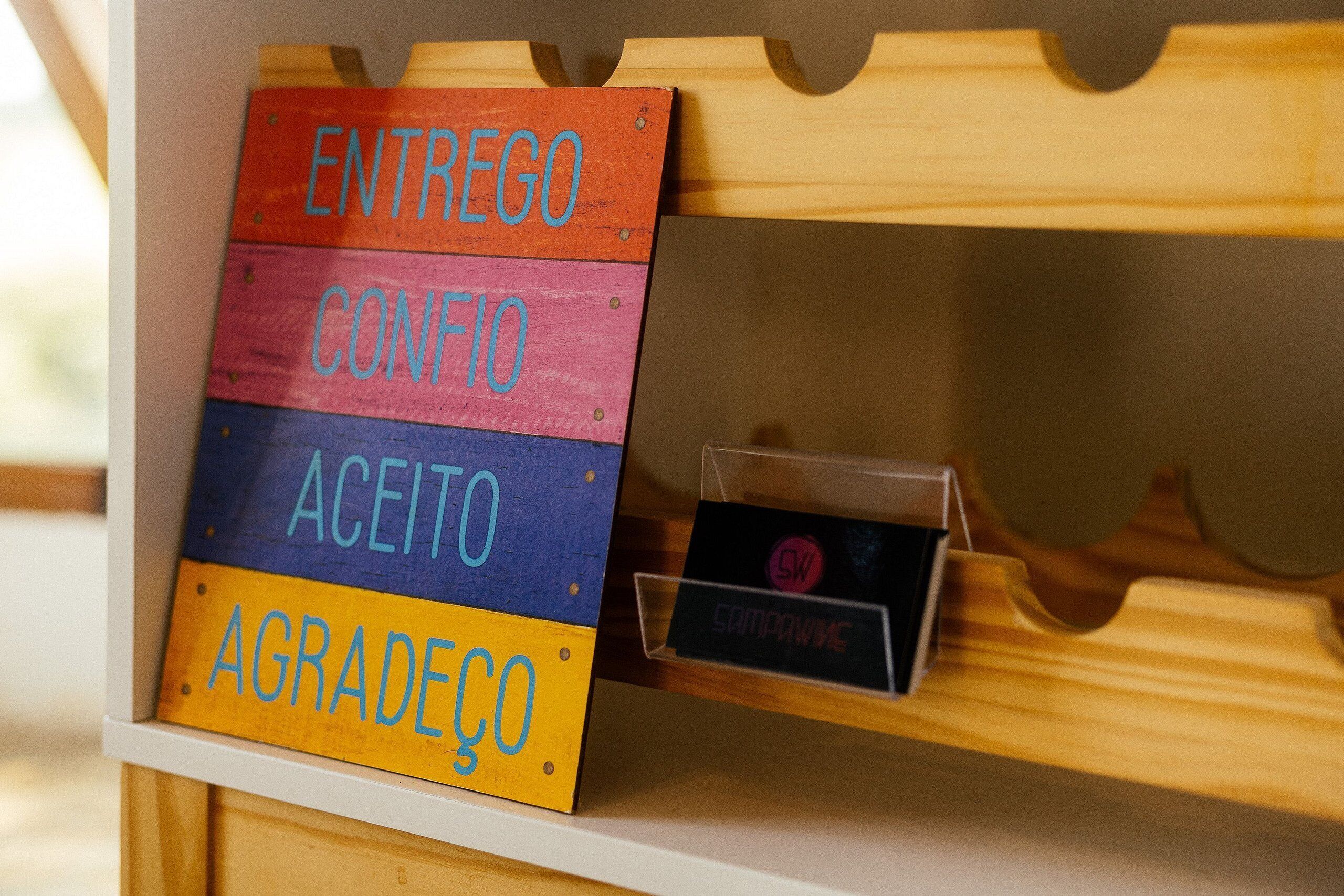 Een houten plank met een bord waarop vier woorden staan: “ENTREGO”, “CONFIDO”, “ACEITO” en “AGRADECÓ”.