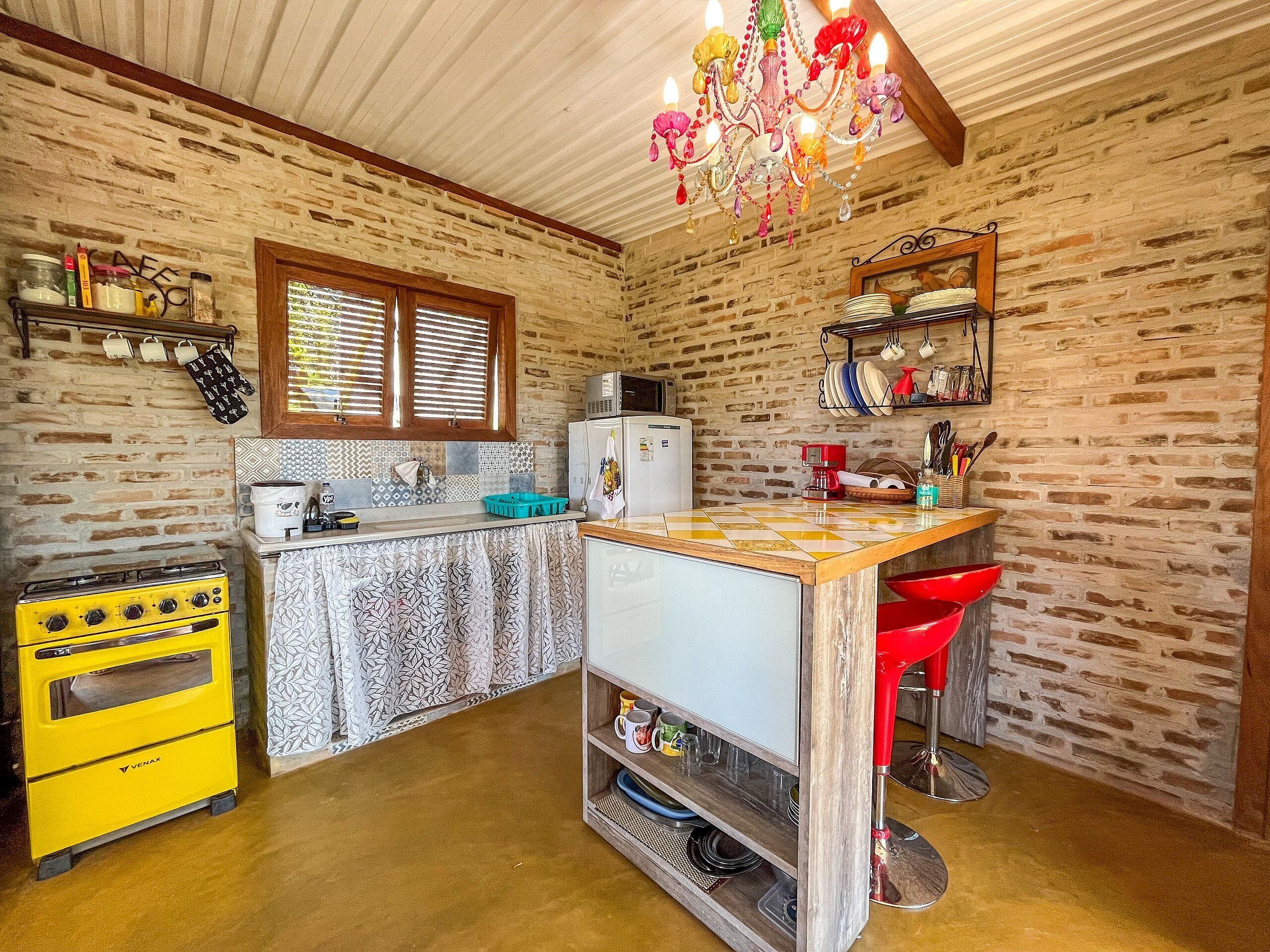 Una cocina compacta con un horno amarillo, un refrigerador y una ventana con persianas.