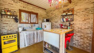 Una cocina compacta con un horno amarillo, un refrigerador y una ventana con persianas.