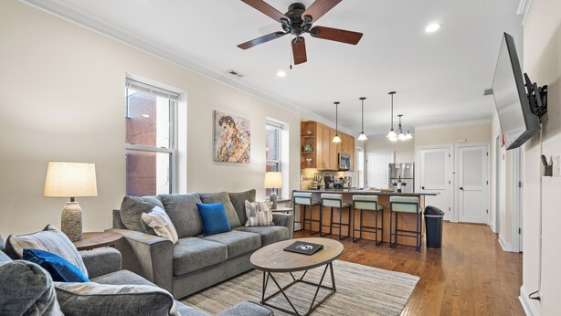 A modern living room with a grey sofa, a coffee table, and a ceiling fan. - North Center Chicago - Walkable - Transit Accessible - King & Queen Beds (Chicago)