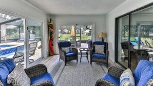 Ein geräumiger Wohnbereich mit Rattanmöbeln, einem blauen Sofa und Blick auf die Terrasse.