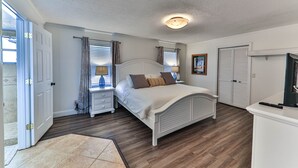 Ein Schlafzimmer mit Bett, Nachttischen, einem Schminktisch, einem Kleiderschrank, einer Tür und einer Deckenleuchte.