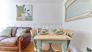 A dining area with a wooden table set for four, surrounded by four chairs.