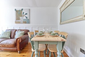 A dining area with a wooden table set for four, surrounded by four chairs.