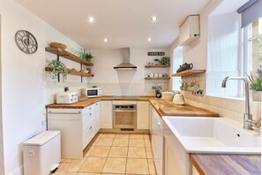 A modern kitchen with white cabinetry, a built-in oven, a microwave, and a coffee bar area.