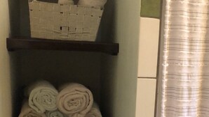 A bathroom with a towel rack holding rolled towels and a basket. - Amazing Jungle Retreat Close to San Ignacio (Bullet Tree Falls)