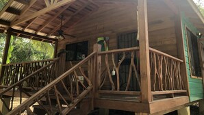A wooden cabin with a balcony, a ceiling fan, and a window with bars. - Amazing Jungle Retreat Close to San Ignacio (Bullet Tree Falls)