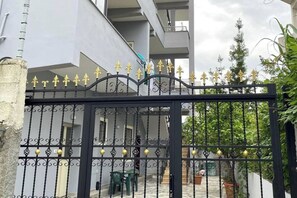 Uma entrada murada com um portão de ferro decorativo e uma escadaria que leva a um edifício.