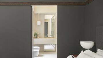 A modern bedroom with a large bed, a bedside table, a nightstand, and a wall-mounted lamp.