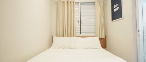 A bedroom with a bed, curtains, an air conditioning unit, and a 'no me' sign on the wall.