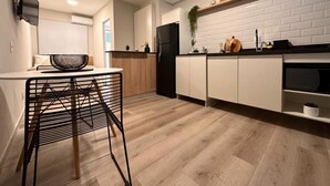 Een moderne keuken met witte kasten, een zwarte koelkast en een houten eettafel met een zwarte stoel.