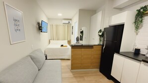 Een knus woongedeelte met een bank, kitchenette en een bed.
