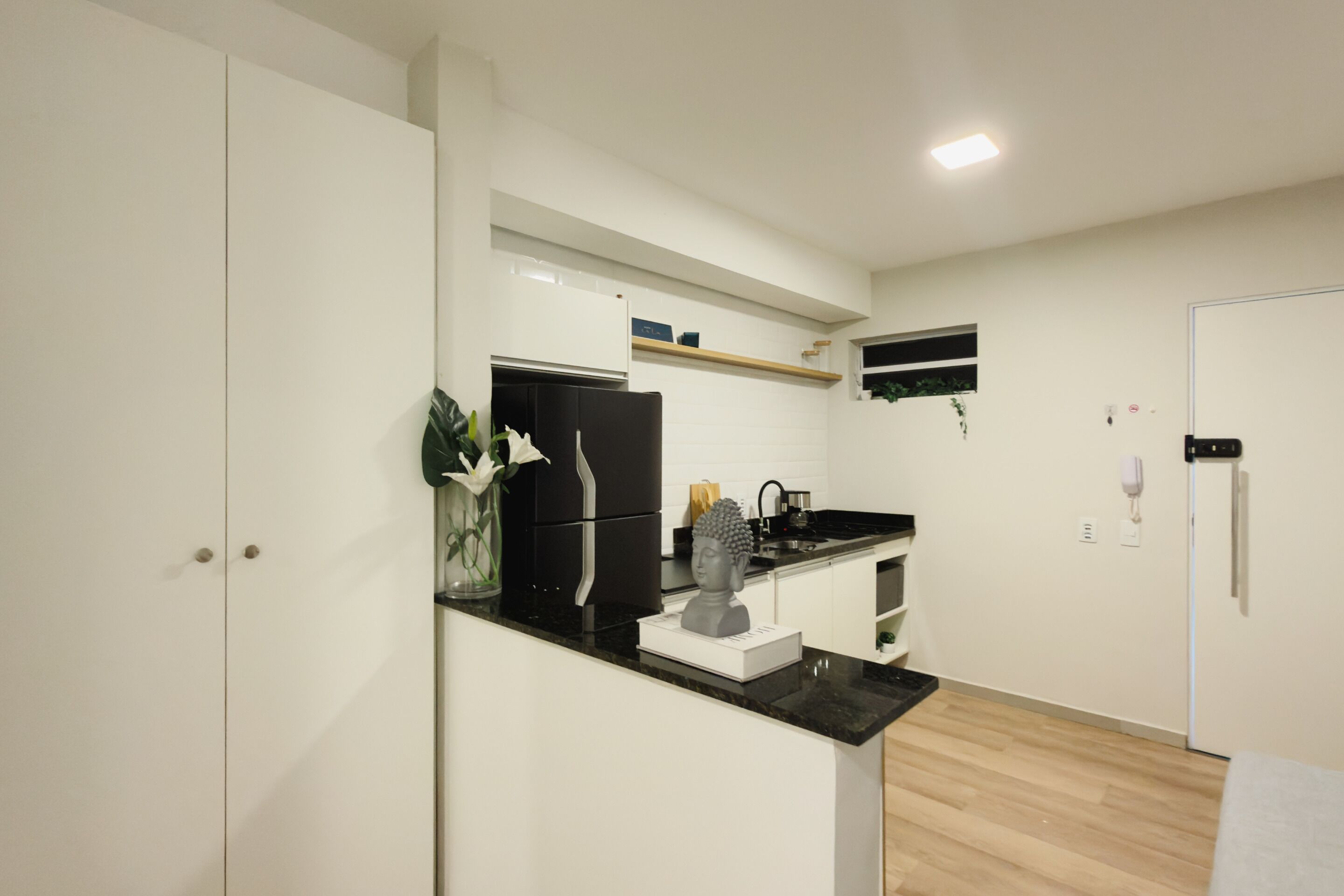 A modern kitchen with white cabinetry, a black countertop, and a built-in oven.