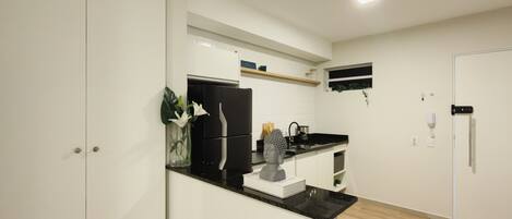 A modern kitchen with white cabinetry, a black countertop, and a built-in oven.