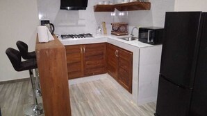 A kitchen with wooden cabinets, a black refrigerator, a microwave, and a gas stove. - Cap Skirring (Cap Skirring)