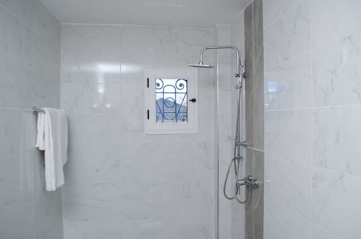 Een douche met een glazen deur, een handdoekhouder en een douchekop.