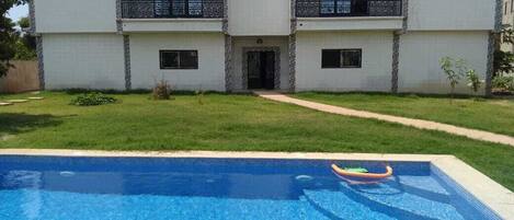Un edificio de dos pisos con una piscina delantera.