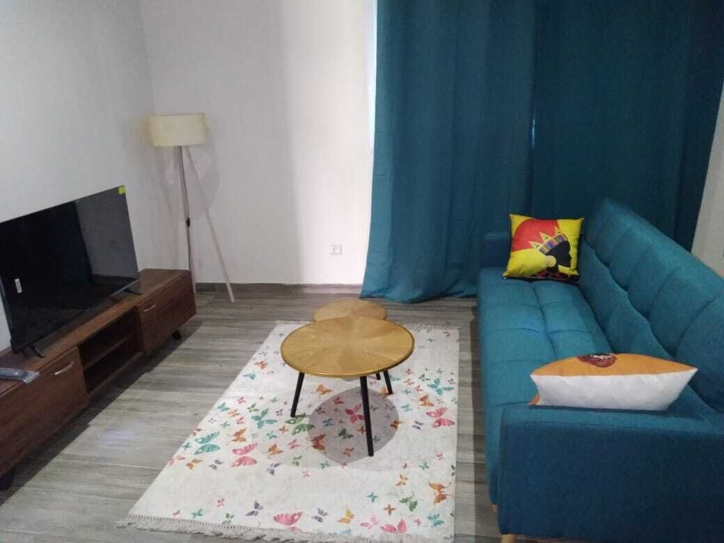A living room with a sofa, a television, a coffee table, and a lamp.
