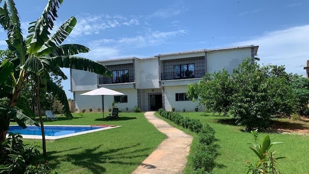 A two-story house with a swimming pool, a concrete pathway, and lush greenery. - Cap Skirring (Cap Skirring)