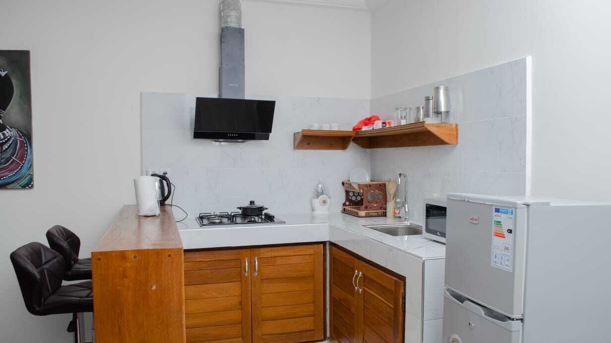 Una cucina compatta con mobili in legno, un fornello a gas, un forno a microonde e un frigorifero.