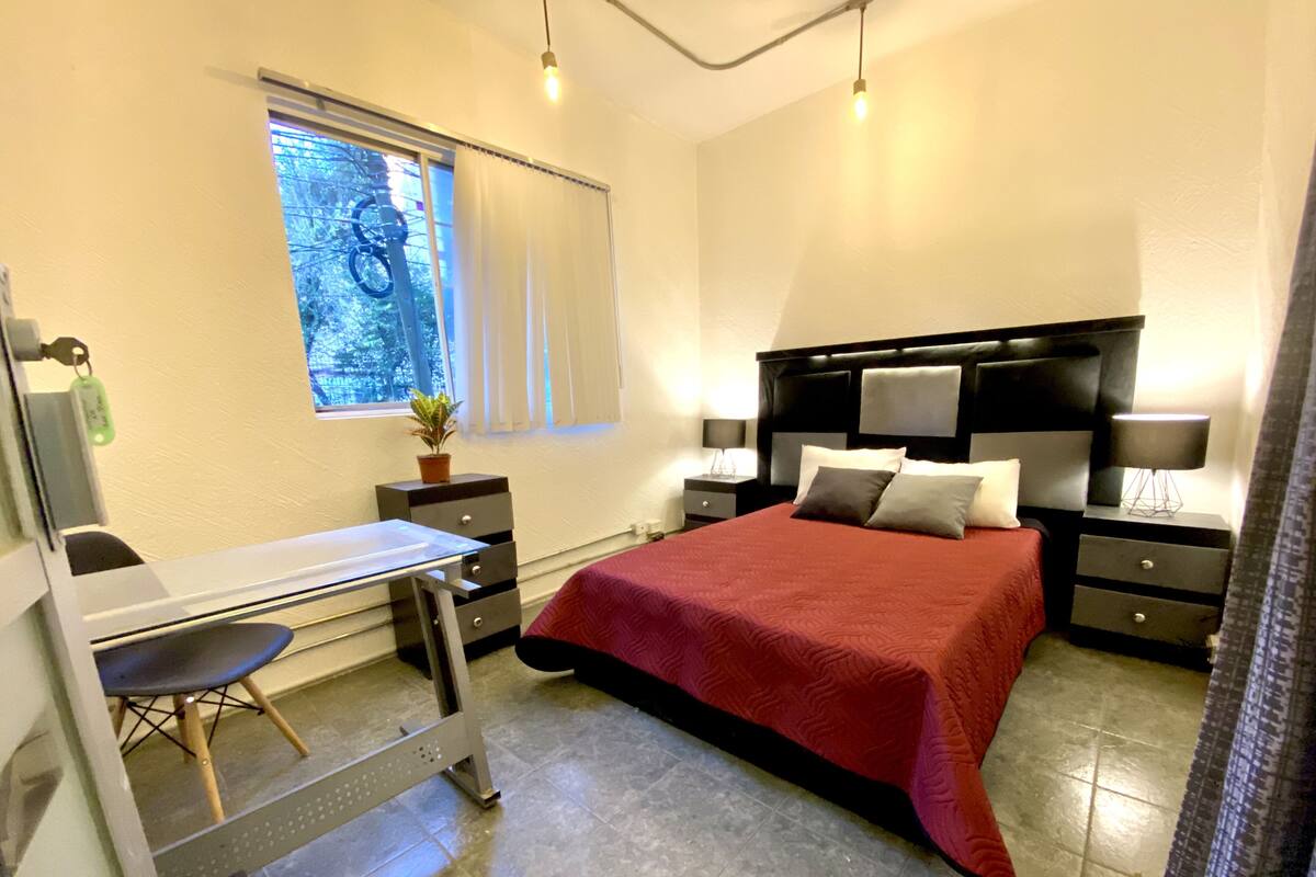 Ein Schlafzimmer mit einem Bett, Nachttischen, einem Schreibtisch und einem Sessel.