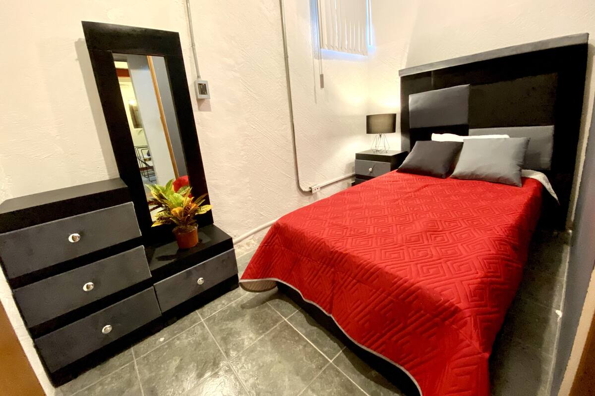 Ein Schlafzimmer mit einem Bett, einem Schminktisch, einem Spiegel und einem Nachttisch.