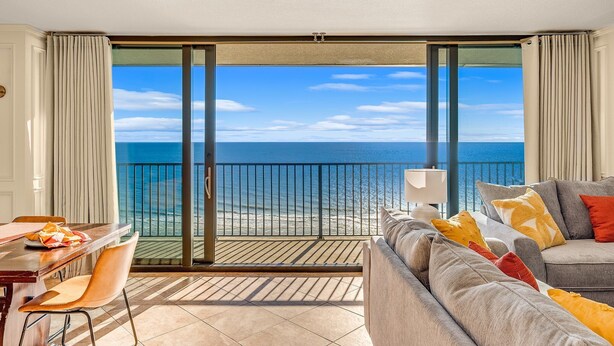 Un balcon avec vue sur la mer, un canapé et une table à manger avec des chaises.