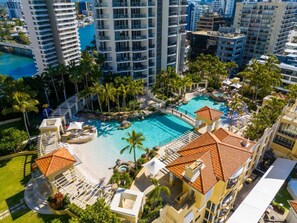 A resort with a large pool, palm trees, and high-rise buildings in the background.