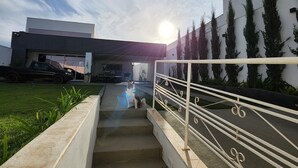 A modern building with a staircase leading to a balcony, surrounded by greenery and a clear sky. - Pousada Luz de Candeia (São João Batista do Glória)