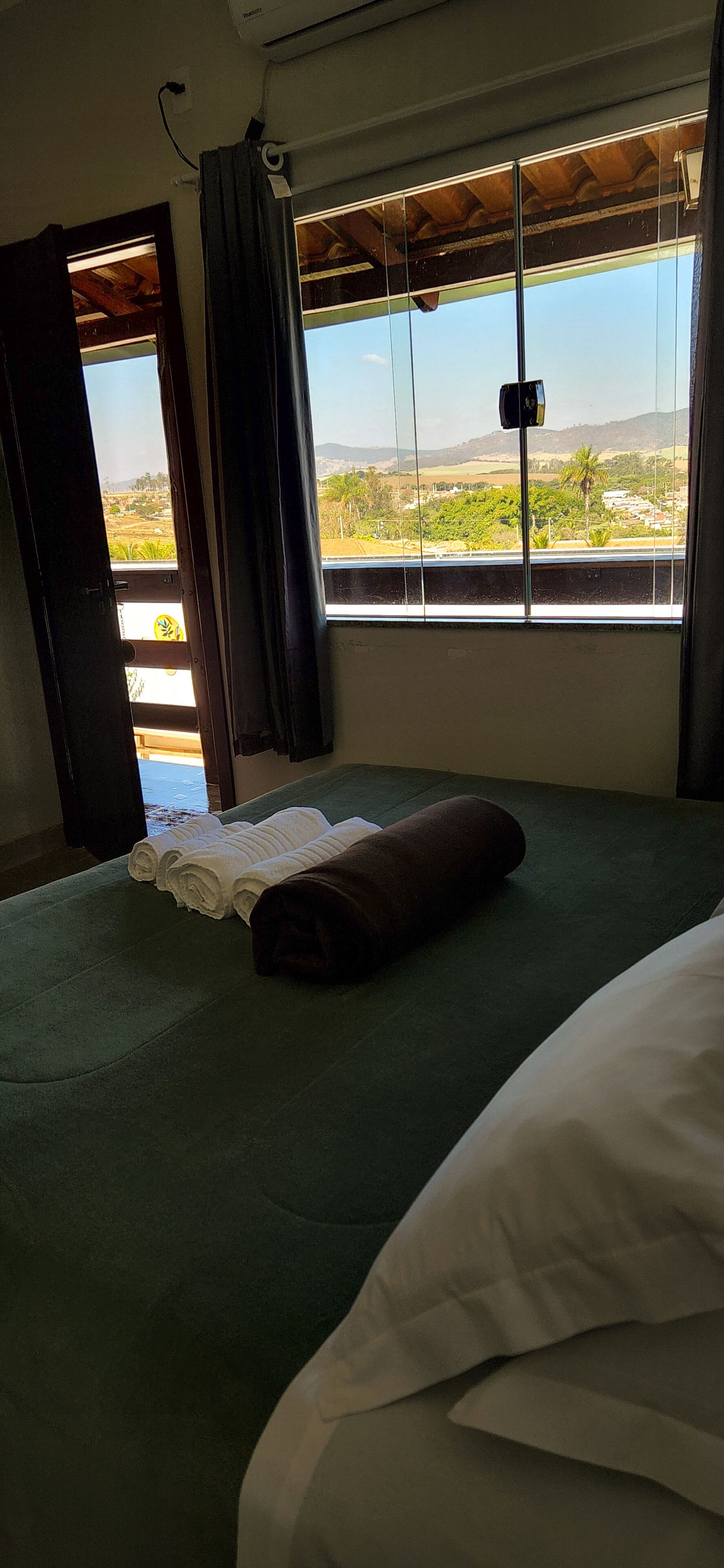 Une chambre d’hôtel avec un lit, une fenêtre donnant sur la campagne et une porte menant à l’extérieur.