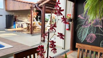 A covered outdoor area with wooden benches, a pool, and a mural of tropical leaves.