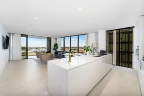 Relax in a spacious living area with a central island kitchen, sliding glass door to a balcony, and a flat-screen TV.