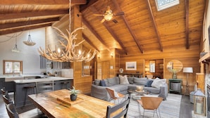 A spacious log cabin interior with a dining area, kitchen, and living room.