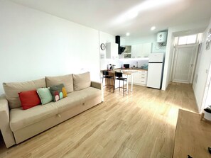 A modern living space with a sofa, a dining area, and a kitchen. - Apartamento D&L Precioso Apartamento Recién Reformado (Costa del Silencio)