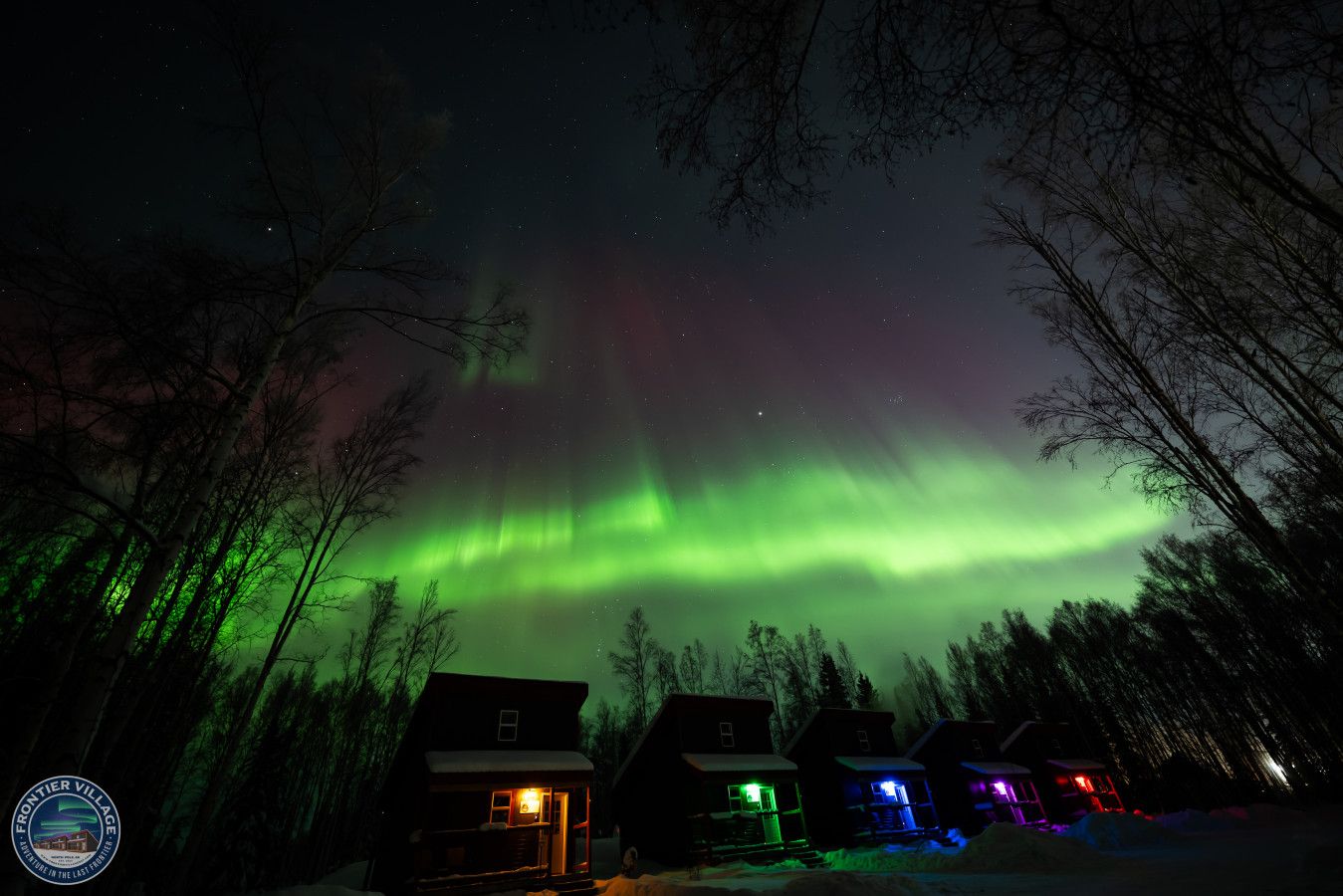 A row of cabins with a view of the Northern Lights.