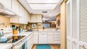 Een moderne keuken met witte kasten, een vaatwasser en een blauw vloerkleed.