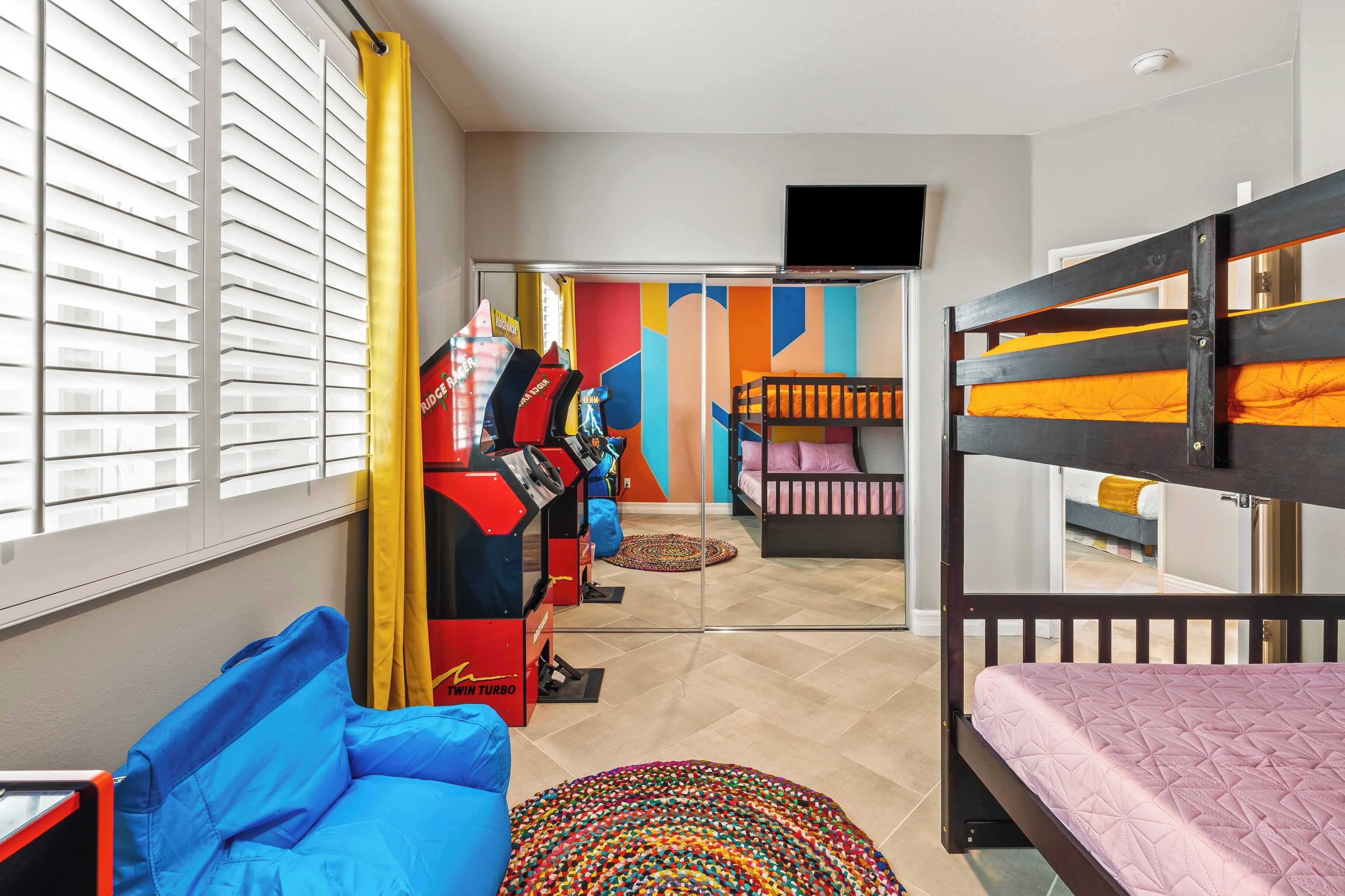 A room with bunk beds, a blue sofa, a treadmill, and a colorful wall.