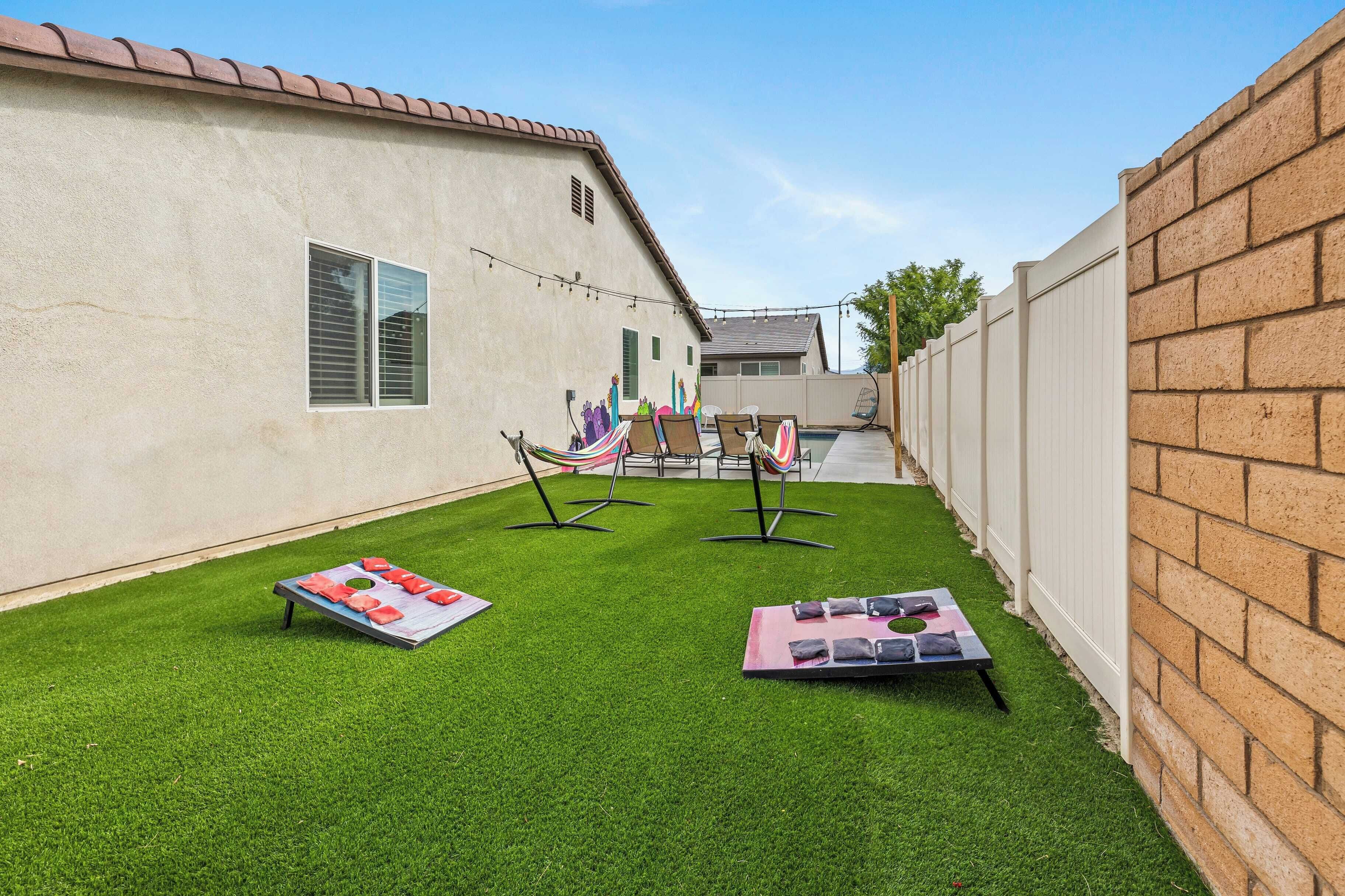 Un jardin avec une pelouse artificielle, un hamac et du matériel d’exercice.