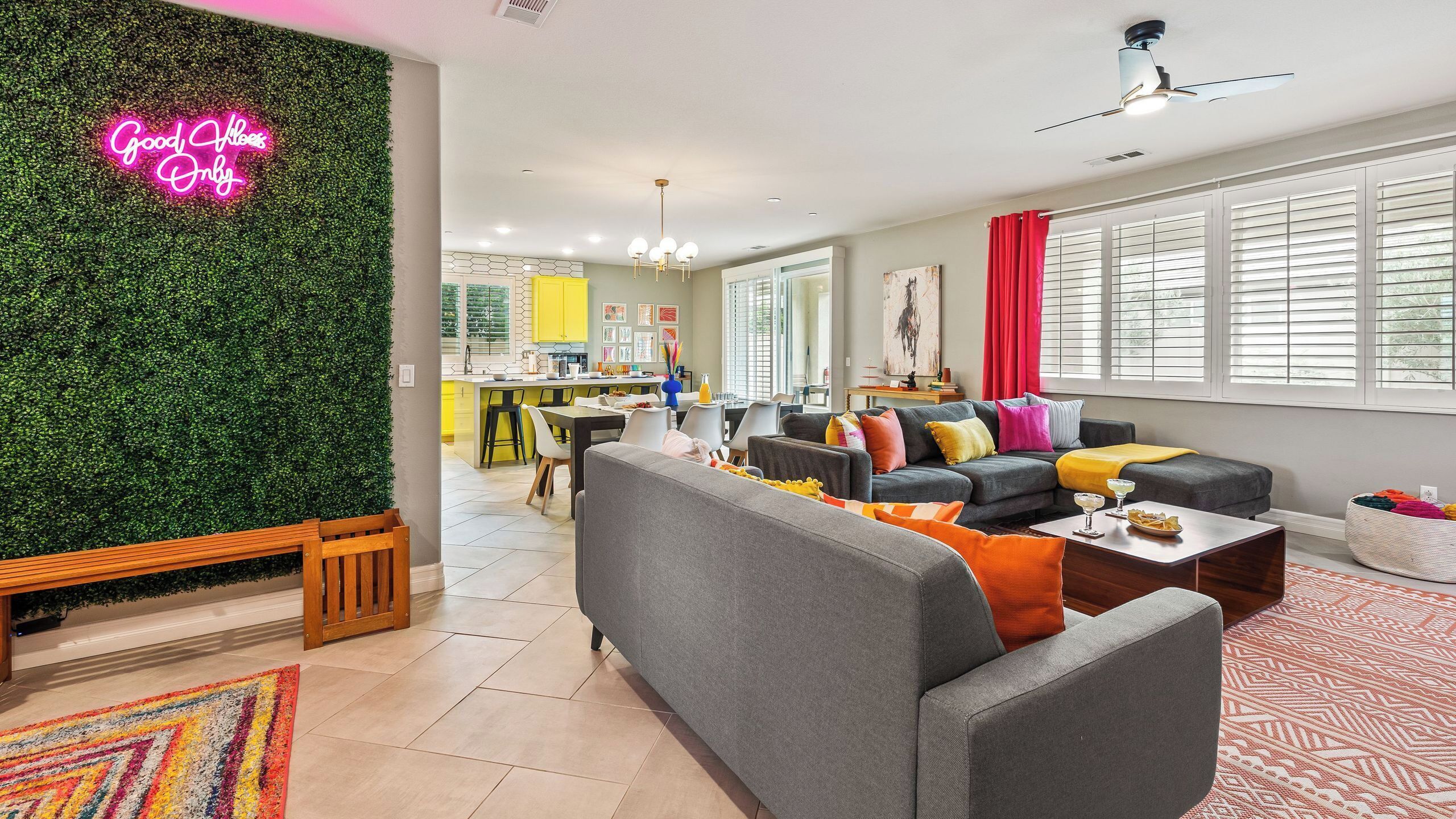 Una sala de estar moderna con un sofá gris, cojines coloridos, una mesa de centro de madera y una alfombra vibrante.