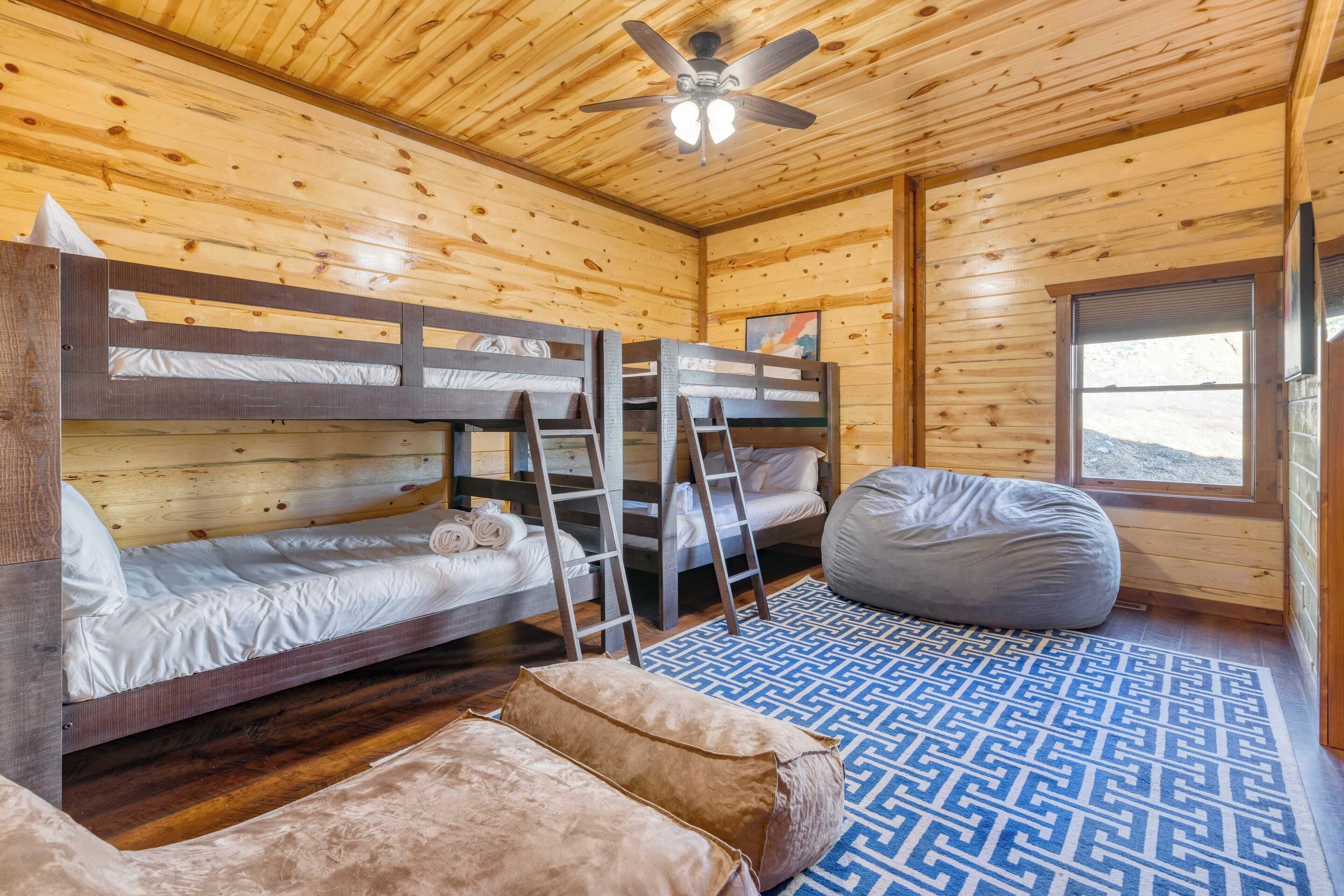 A wooden cabin room with bunk beds, a bean bag, and a patterned rug.