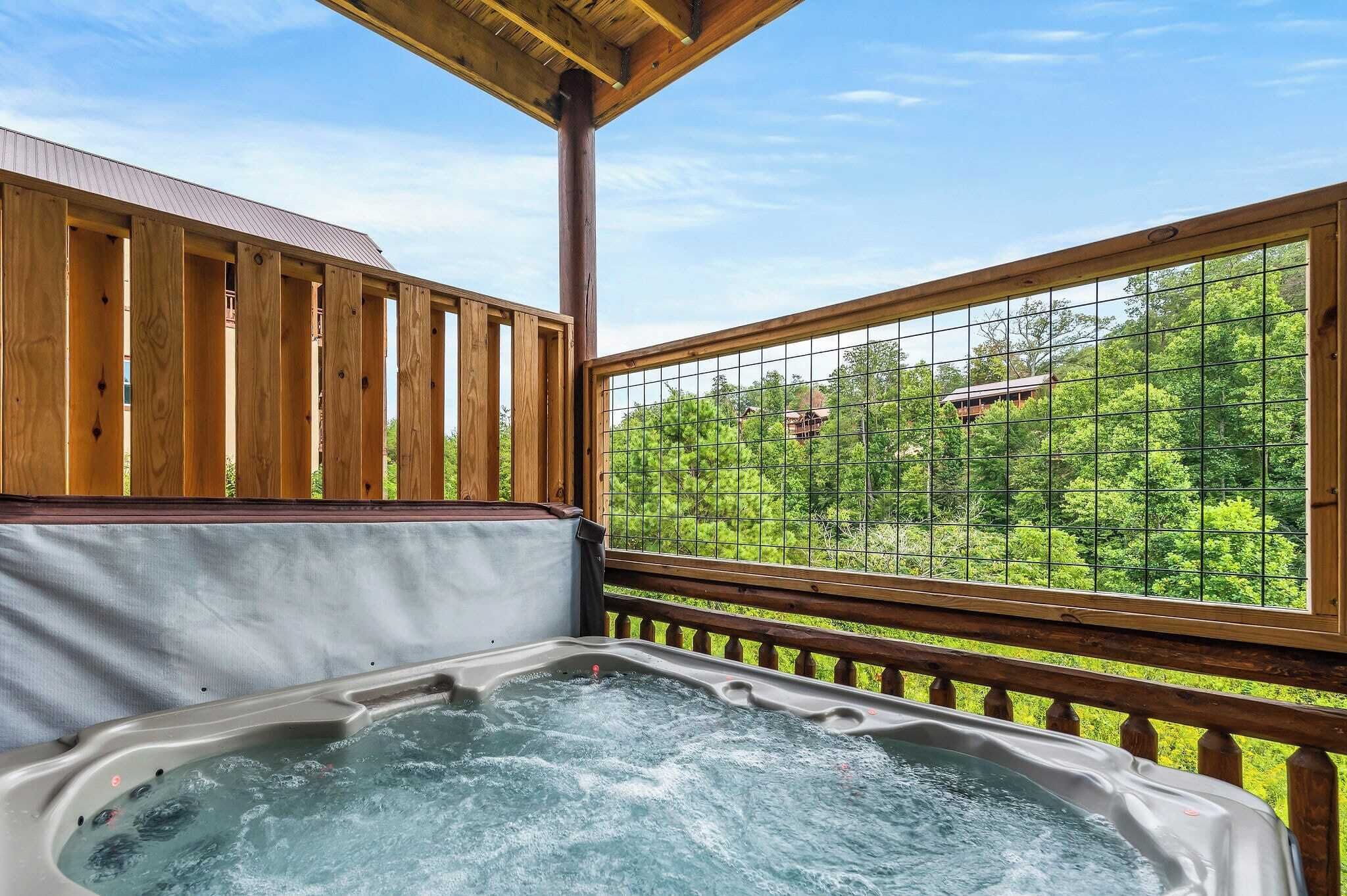 A wooden deck with a hot tub and a view of a lush green landscape.