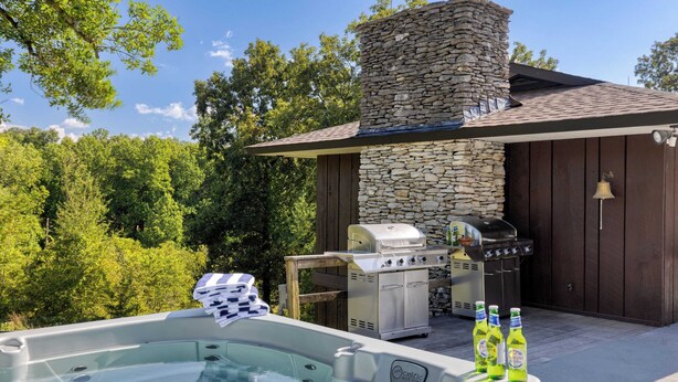 A hot tub with a stone chimney, a grill, and bottles of beer. - Amber Refresh by Avantstay Pool and Hot Tub (New Market)
