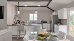 A modern kitchen with a central island, pendant lighting, and a view of the outdoors. - Amber Refresh by Avantstay Pool and Hot Tub (New Market)